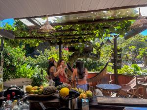 three women sitting at a table in a garden at Pousada Tiririca Surf in Itacaré +168 photos
