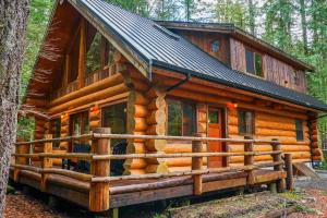 a log cabin in the woods with a metal roof at Wilderness Retreat in Glacier