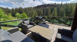 a deck with a table and chairs and an umbrella at Forest House in Yablunytsya