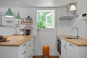 a kitchen with white cabinets and a sink and a window at 1195-Ringkobing-Risbjergvej-84 in Ringkøbing +18 photos
