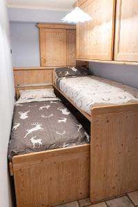 two beds in a room with wooden cabinets at Appartamento TreZero in Valfurva