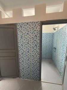 a bathroom with a door and a tiled wall at Atlantic Hostel in Essaouira +69 photos