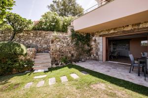 a backyard with a stone wall and a table and chairs at BeLocations - Aldia Garden Seaview in Puntaldia