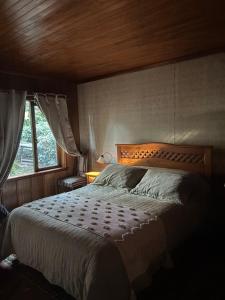a bedroom with a bed with a wooden headboard and a window at cabañas kiel in Llanquihue