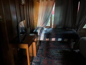 a bedroom with a bed and a tv and a window at cabañas kiel in Llanquihue