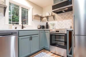 a kitchen with blue cabinets and stainless steel appliances at Little Haven Cottage in Glacier