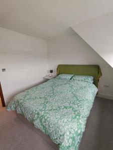 a bed with a green comforter in a bedroom at Kilby close in Edgware