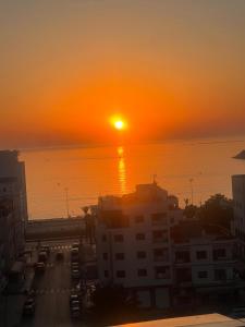 a sunset over the ocean with a city at Mdiaq in M'diq