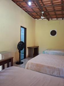 a room with two beds and a fan and a window at Encanto na Mata in Mata de Sao Joao