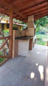 a patio with an outdoor kitchen with a wooden roof at Encanto na Mata in Mata de Sao Joao