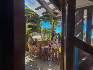 a group of people sitting at a table on a deck at Pousada Tiririca Surf in Itacaré