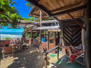 a house on the beach with two people laying on the deck at Pousada Tiririca Surf in Itacaré