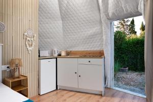 a kitchen with white cabinets in a room with a window at Geo heaven glamp in Aïtánia