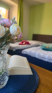 a table with a vase of flowers and a book at Ferienwohnungen auf einem rustikalen 3 Seitenhof in Göda