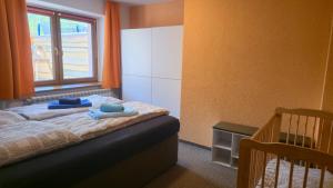 a bedroom with a bed and a window and a crib at Ferienwohnungen auf einem rustikalen 3 Seitenhof in Göda