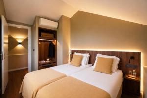 a bedroom with a large bed with white sheets and pillows at Piu Bella in Fajã da Ovelha