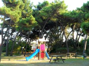 a playground with a slide and two picnic tables at Villa Caprera in Rosolina Mare