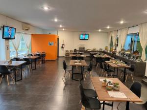 a dining room with tables and chairs and televisions at Hotel Solé Plaza Guadalajara in Guadalajara