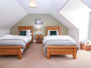a attic bedroom with two beds and a window at St Kilda in Ballater