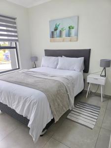 a white bedroom with a large bed with white sheets at 77 on Par in Boksburg