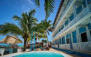 a swimming pool next to a building with palm trees at El Faro Beach Front by ÓOL Hotels in Holbox Island