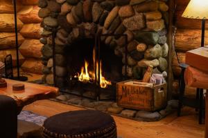 ein Kamin in einer Blockhütte mit einem Feuer darin in der Unterkunft Forest Embrace in Glacier