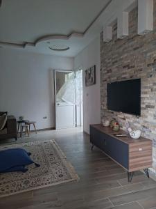 a living room with a television on a brick wall at maison entre forêt et mer in Raʼs al Jabal
