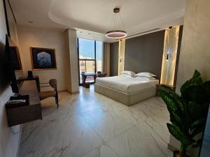 a bedroom with a bed and a table and a chair at 皇冠半岛酒店 - TAJ Boutique Hotel in Baghdād