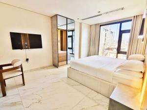 a bedroom with a bed and a desk and a tv at 皇冠半岛酒店 - TAJ Boutique Hotel in Baghdād