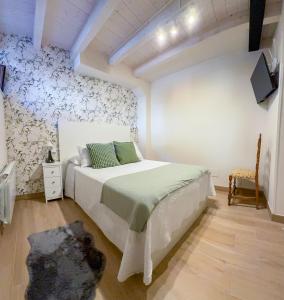 a bedroom with a white bed and a wall at Apartamentos San Roque in Arenas de Cabrales