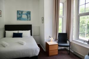 a bedroom with a bed and a chair and windows at City Centre Guest House - Gloucester Park in Gloucester +26 photos