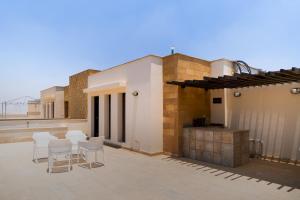 a patio with white chairs and a grill on a building at 33A4. Rooftop Studio w Terrace Green Views in Sheikh Zayed