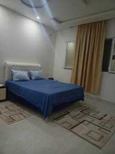 a bedroom with a blue bed and a window at maison entre forêt et mer in Raʼs al Jabal