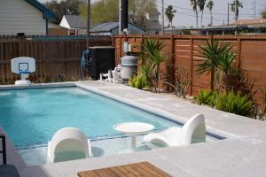 a swimming pool with chairs and a table in a backyard at Astra B, Designer 3BR, Arcade, Heated Pool in Port Isabel