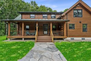 a log cabin with a porch and stairs to the front at Log Cabin Fireplace Upper Valley - Wooded Chalet in Hartland +81 photos