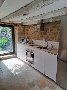 a kitchen with white appliances and a large window at Instant Lot Maison pierre insolite Piscine Nature in Strenquels