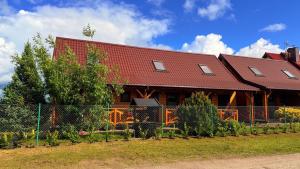 a house with a red roof and a fence at Domki Marlin in Rewal
