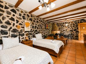 a bedroom with two beds and a stone wall at La Tanquera y Las Rosas in Los Realejos