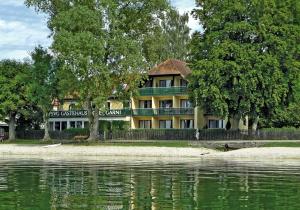 ein Gebäude neben einem Wasserkörper in der Unterkunft Seespitz Gästehaus in Herrsching am Ammersee