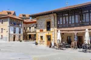 a building with tables and umbrellas on a street at Apartamentos San Roque in Arenas de Cabrales