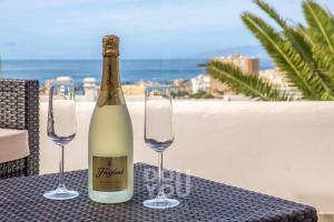 a bottle of wine and two wine glasses on a table at Holiday Apartments Oasis in Los Cristianos