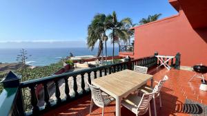a balcony with a wooden table and chairs and the ocean at Finca La Romera in La Orotava