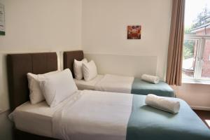 a hotel room with two beds and a window at City Centre Guest House - Gloucester Park in Gloucester