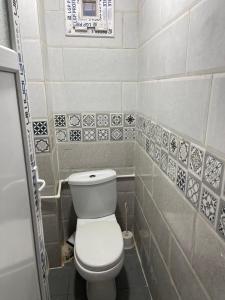 a bathroom with a toilet and a tile wall at Front de mer salamndre in Mostaganem