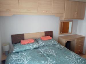 a bedroom with a bed with two orange pillows on it at Cairnryan - Loch Ryan View in Cairnryan