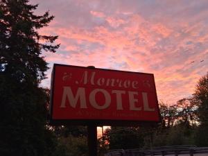a sign for a motel with a sunset in the background at Monroe Motel Near Seattle Everett WA in Monroe