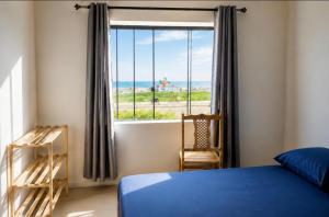 a bedroom with a bed and a window with the ocean at Cibratel Hostel - Pé na Areia in Itanhaém