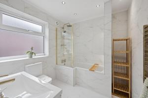 a white bathroom with a shower and a sink at Spacious Modern home in the heart of Whitefield - Private Driveway Parking in Whitefield +19 photos