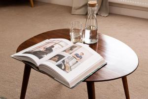 a book on a table with glasses and a bottle at Town Centre - Elegant Stylish Apartment in Shrewsbury