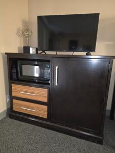 a entertainment center with a microwave and a tv on it at Monroe Motel Near Seattle Everett WA in Monroe
